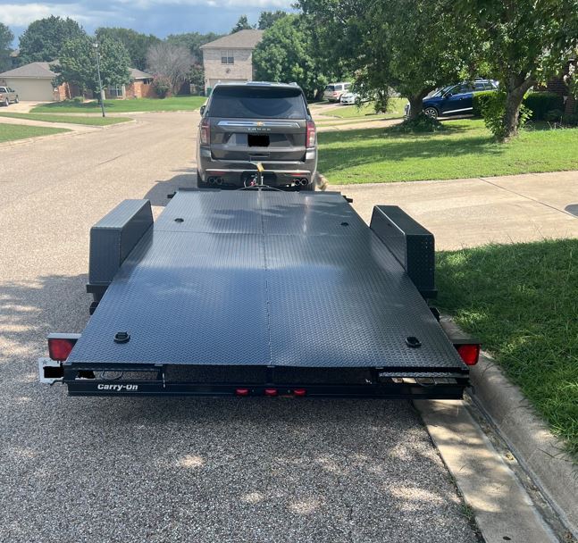 Side view of flatbed car hauler trailer with safety chains