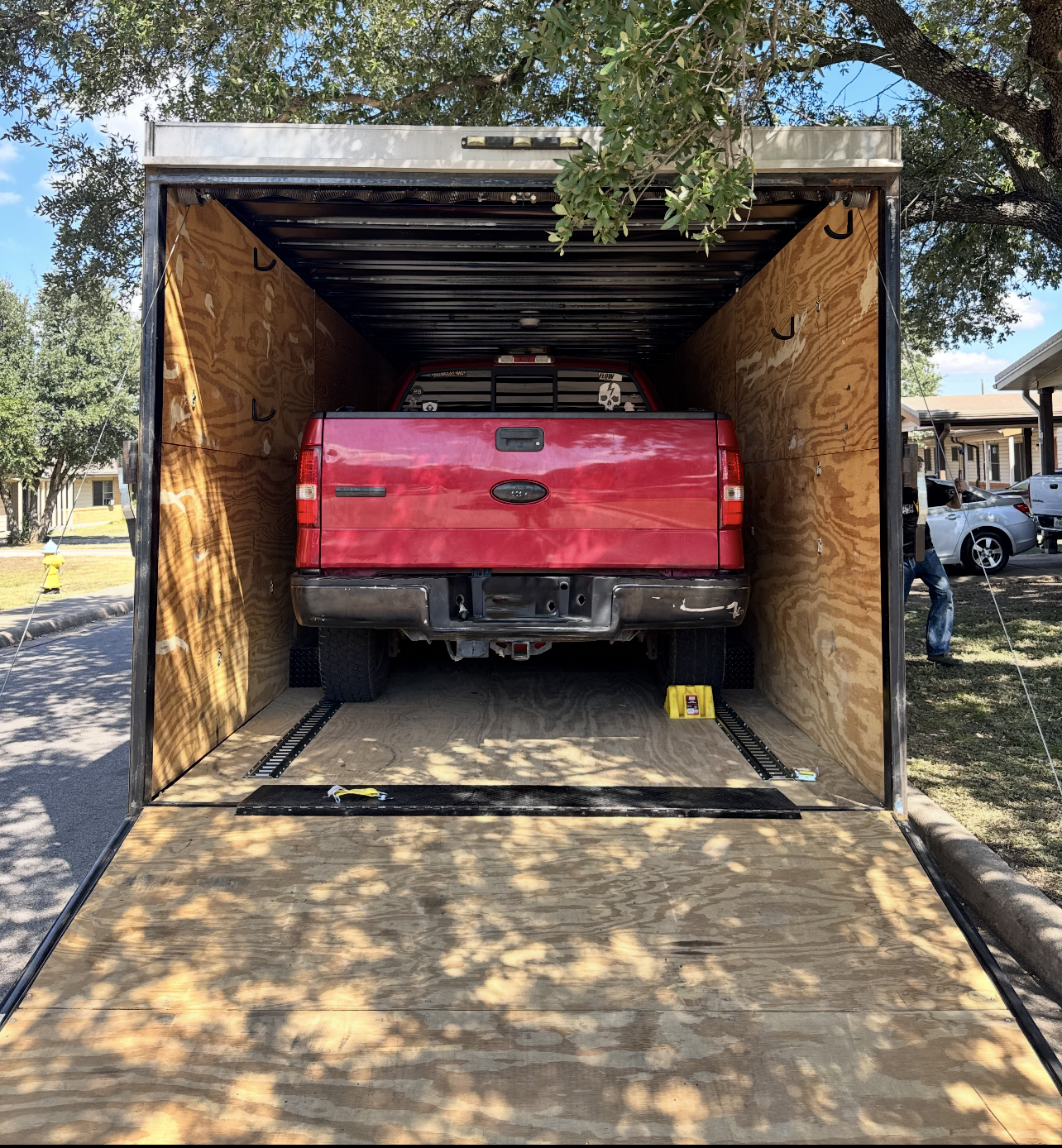 Empty gooseneck trailer interior showing plywood walls and aluminum floor with tie-down tracks
