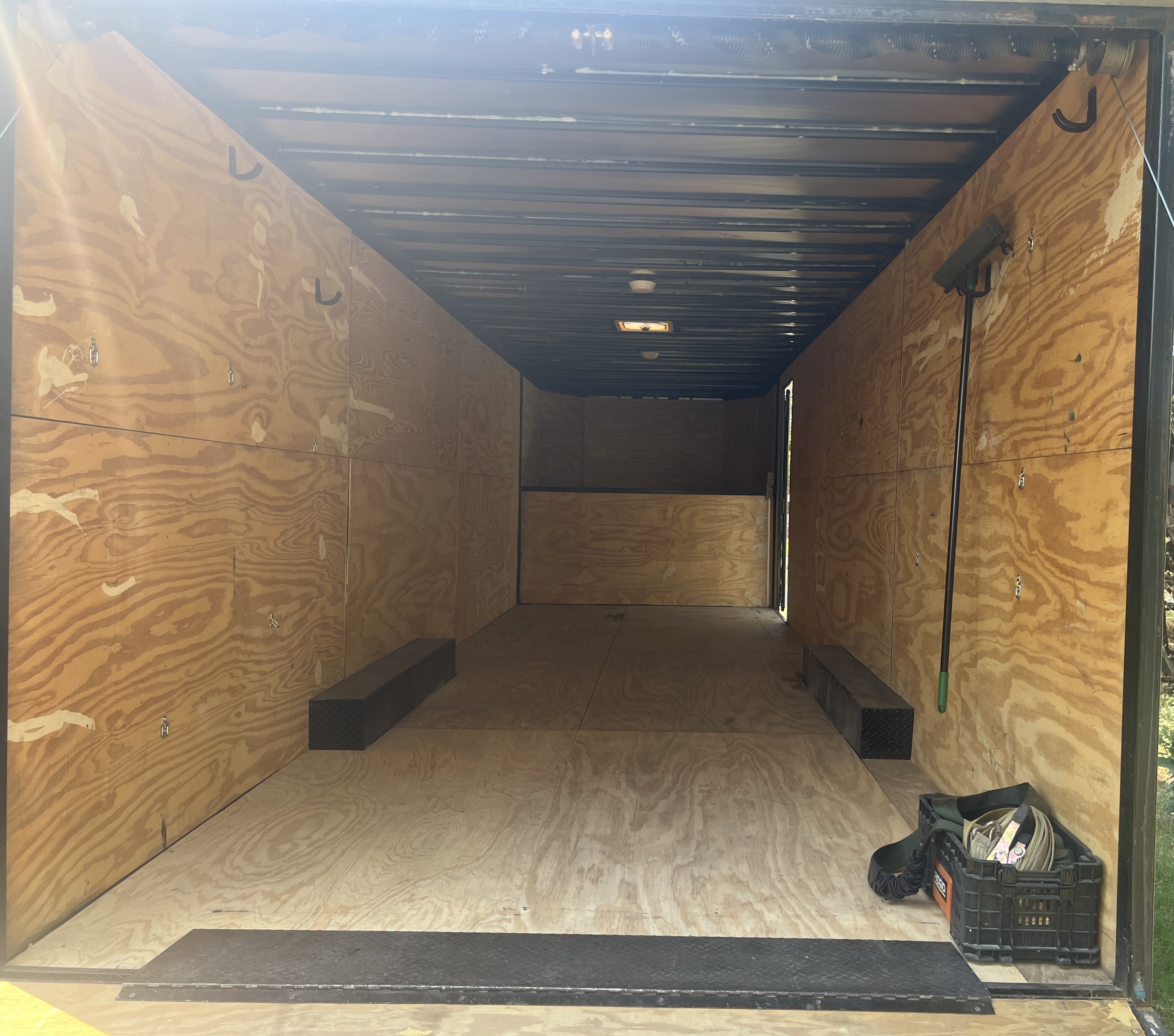 Gooseneck trailer interior from rear showing depth and storage compartments along sides